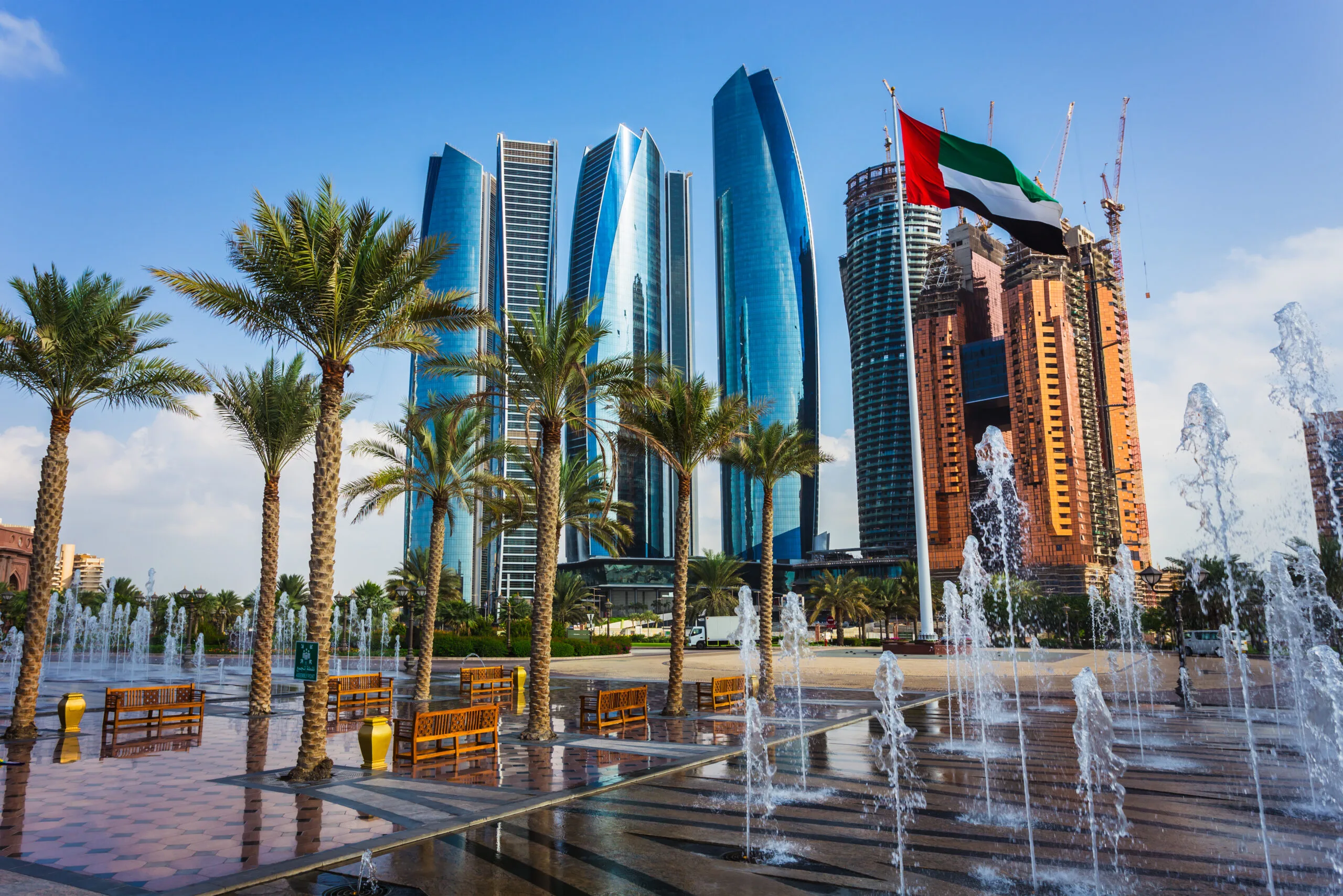 Abu Dhabi skyline with UAE flag, palm trees and fountains