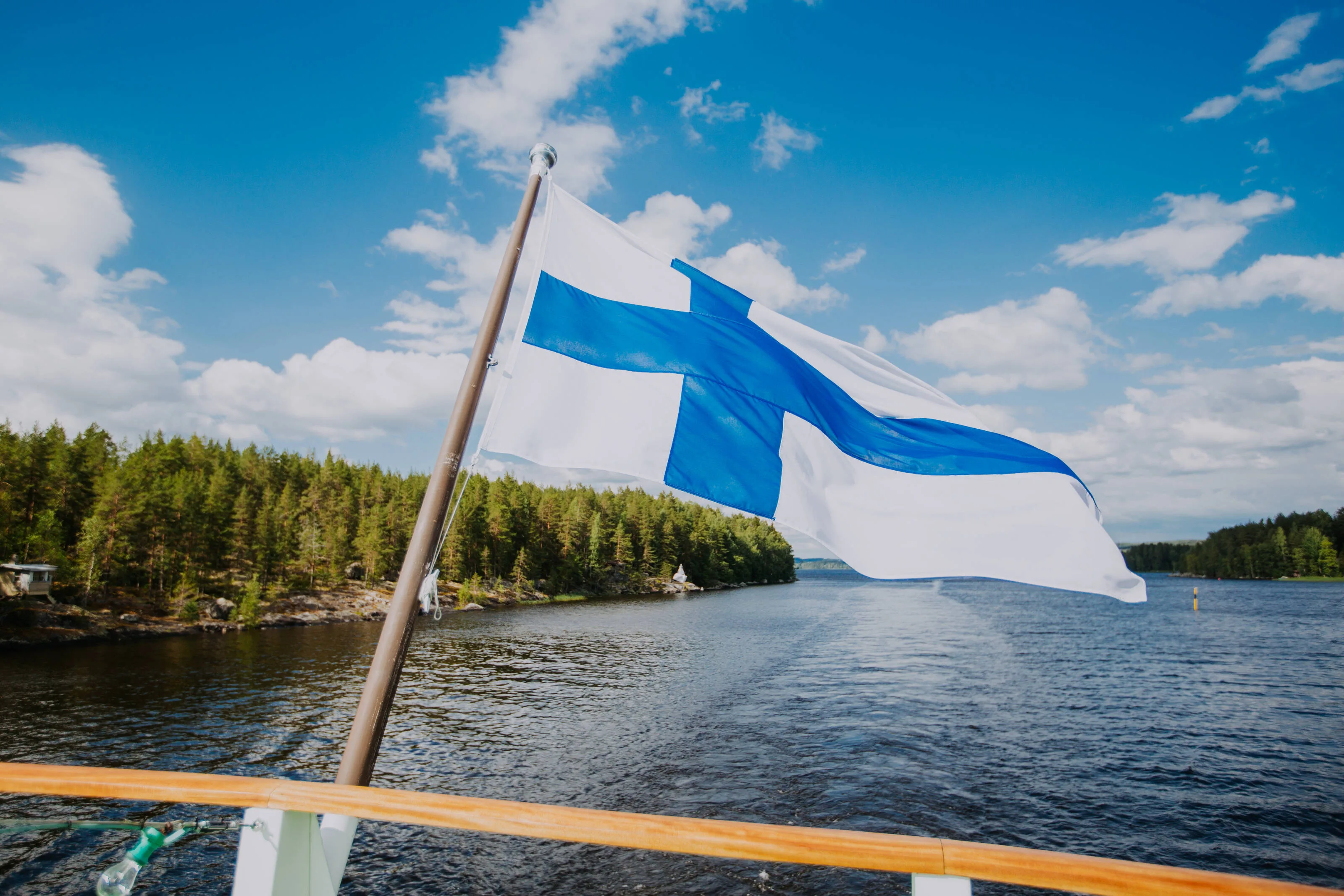 Finnish flag flying over a lake and forest