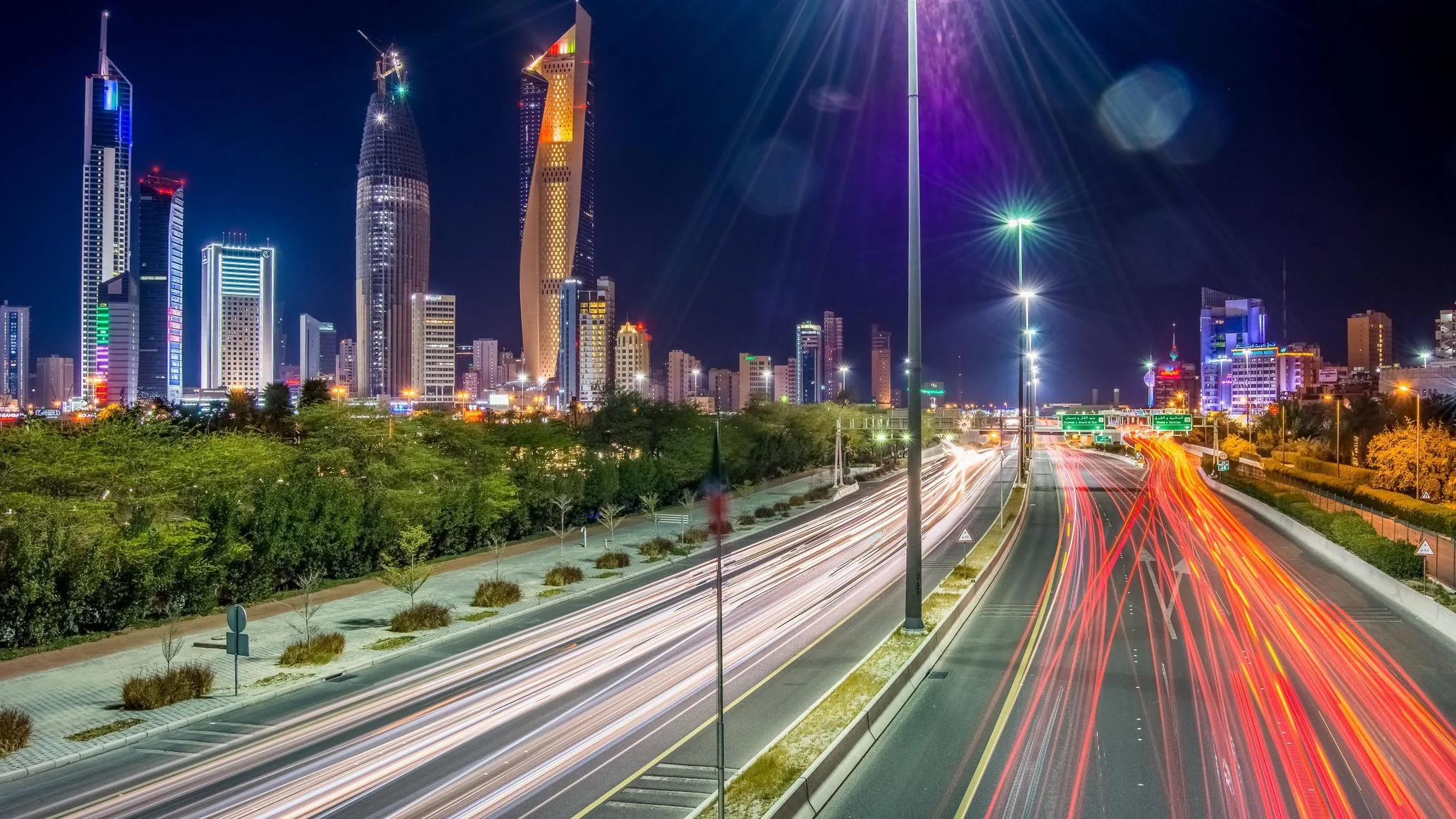 Kuwait City skyline at night with illuminated towers and traffic trails