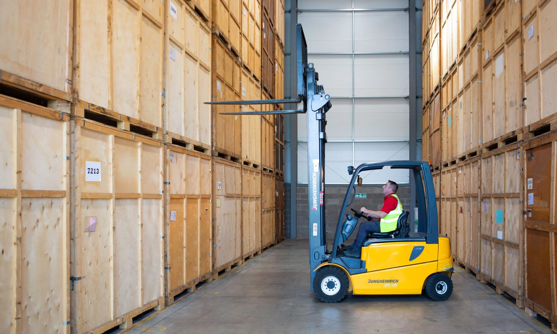 Forklift moving wooden storage crates in a warehouse